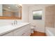 Well-lit bathroom with white cabinets, quartz countertop, large framed mirror, and a combined tub and shower at 5897 Carriage Dr, Sarasota, FL 34243