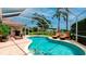 Screened pool area with lounge chairs, palm trees and view of a pond with fountain feature at 5897 Carriage Dr, Sarasota, FL 34243