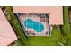 Aerial view of screened-in pool with kidney shape, brick patio, and manicured lawn and shrubbery at 5897 Carriage Dr, Sarasota, FL 34243