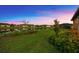 Picturesque backyard with lush green lawn, tranquil pond, and stunning sunset views at 6791 Alstead Cir, Bradenton, FL 34202