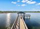 Scenic lake view with a wooden dock featuring a covered seating area, perfect for waterside enjoyment at 6791 Alstead Cir, Bradenton, FL 34202