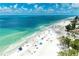 Stunning aerial view of a vibrant beach with clear blue water, white sand, and scattered beachgoers enjoying the sun at 6804 19Th W Ave, Bradenton, FL 34209