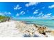 Scenic beach view with white sand, turquoise water, rock barriers, and a clear blue sky above at 6804 19Th W Ave, Bradenton, FL 34209