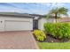 Close-up of the home's three-car garage, landscaped entry, and black front door with sidelight at 7119 67Th E Ter, Bradenton, FL 34203