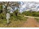 Entrance to a nature trail, featuring a sign, gravel path, lush greenery, and a canopy of trees at 7119 67Th E Ter, Bradenton, FL 34203