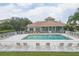 Community pool with lounge chairs and tables surrounded by a white fence and a clubhouse in the background at 7119 67Th E Ter, Bradenton, FL 34203