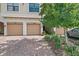 View of the garages of the townhome showcasing a brick paved driveway and mature landscaping at 7325 Skybird Rd # 399, Bradenton, FL 34209