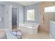 Bathroom showcasing a tub and glass-enclosed shower with beige tiles and soft blue walls at 7542 Windy Hill Cv, Bradenton, FL 34202