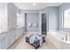 Bright bathroom featuring a tub, vanity with granite counters and cabinetry, and soft blue walls at 7542 Windy Hill Cv, Bradenton, FL 34202