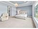 Bright main bedroom with decorative tray ceiling, chandelier, and large windows at 7542 Windy Hill Cv, Bradenton, FL 34202