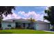 Charming single story home featuring a lush lawn, lovely landscaping, and a light blue exterior at 831 Palmetto Ne Dr, Port Charlotte, FL 33952
