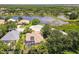 Stunning aerial view of a home with a screened pool, lush landscaping, and a serene lake backdrop at 866 Oak Briar Ln, Osprey, FL 34229