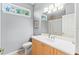 Bright bathroom features vanity, toilet and decorative mirror; natural light from the window at 866 Oak Briar Ln, Osprey, FL 34229