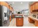 Stylish kitchen with stainless steel appliances, island with granite countertop, and warm wooden cabinetry at 866 Oak Briar Ln, Osprey, FL 34229