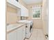 Functional laundry room with modern washer and dryer, built-in cabinets, and a utility sink at 866 Oak Briar Ln, Osprey, FL 34229