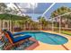 Inviting screened pool area with lounge chairs, umbrella, and lush landscaping at 866 Oak Briar Ln, Osprey, FL 34229