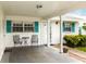 Charming covered front porch with teal shutters, seating area and a neutral color palette at 9412 Concord Cir, Bradenton, FL 34210