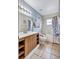 A bright bathroom featuring tiled floors, wood vanity, decorated shower curtain, and grab bars on the toilet at 1126 Barclay Wood Dr, Ruskin, FL 33570