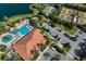 Aerial view of a community pool, clubhouse, tennis courts, and parking lot with lake in the background at 13338 Torresina Ter, Lakewood Ranch, FL 34211