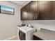 Functional laundry room with modern washer, dryer, overhead cabinets, and countertop space at 13338 Torresina Ter, Lakewood Ranch, FL 34211