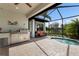 An outdoor kitchen with grill, beverage cooler, sink, and ample countertop space in a screened-in patio at 13338 Torresina Ter, Lakewood Ranch, FL 34211