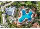 Aerial view of a luxurious pool area surrounded by palm trees, lounge chairs, and a covered bar and outdoor dining area at 13338 Torresina Ter, Lakewood Ranch, FL 34211