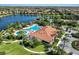 Aerial view of a community pool and clubhouse next to a large lake and lush landscaping at 13338 Torresina Ter, Lakewood Ranch, FL 34211