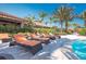 Comfortable poolside loungers with orange cushions next to a sparkling pool surrounded by palms at 13338 Torresina Ter, Lakewood Ranch, FL 34211