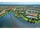 Aerial view featuring a pool, clubhouse, tennis courts, a gazebo, and a scenic lake at 13609 Messina Loop # 104, Bradenton, FL 34211