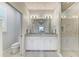 Bright bathroom with double vanity, granite counters, white cabinets, and a glass enclosed shower at 13609 Messina Loop # 104, Bradenton, FL 34211