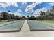 Outdoor bocce courts are framed by lush landscaping and palm trees beneath a blue sky with scattered clouds at 13609 Messina Loop # 104, Bradenton, FL 34211