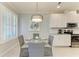 Bright dining area features a modern light fixture, a round glass table, and white cabinets at 13609 Messina Loop # 104, Bradenton, FL 34211