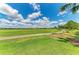 Scenic golf course view with a walking path and lush greenery under a bright, cloud-filled sky at 13609 Messina Loop # 104, Bradenton, FL 34211