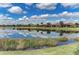 Scenic view of homes reflected in a calm pond, set against a backdrop of a bright blue sky with fluffy white clouds at 13609 Messina Loop # 104, Bradenton, FL 34211