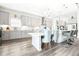 Modern kitchen with gray cabinets, an island with bar stool seating, and a table with tufted chairs at 13871 Heartwood Way, Parrish, FL 34219
