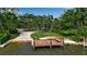 View of a private wooden dock with built-in seating, grassy area and mature trees at 1808 Coquina Dr, Sarasota, FL 34231