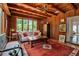 Cozy living room with wood walls, beamed ceiling, terracotta floors, and large windows at 1808 Coquina Dr, Sarasota, FL 34231