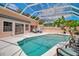 A screened-in pool with blue water is surrounded by a white deck, lounge chairs, and a beautiful flowering tree at 1808 Coquina Dr, Sarasota, FL 34231