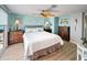 Bright bedroom features wood-look floors, ceiling fan, and coastal decor with comfortable furniture and a sliding glass door to the outside at 2107 Palma Sola Blvd # 7, Bradenton, FL 34209