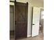 Stylish interior with a wooden sliding barn door, a white paneled door, and plank flooring at 2311 W 52Nd Ave Drive, Bradenton, FL 34207
