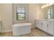 Bathroom showcasing a soaking tub, window with blinds, and white cabinets at 2469 Paradise Plum Dr, Sarasota, FL 34240