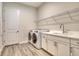 Well-equipped laundry room with modern washer, dryer, utility sink, and storage cabinets at 2469 Paradise Plum Dr, Sarasota, FL 34240