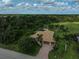 Aerial view of home with brick driveway, mature trees and a well-manicured lawn at 306 Country Meadows Way, Bradenton, FL 34212