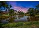 Scenic view of a tranquil pond at sunset, surrounded by lush greenery and neighborhood houses at 3362 Sandleheath # 12, Sarasota, FL 34235