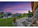Backyard waterfront view with brick patio, chairs, green grass, and boat dock against a beautiful sunset at 3876 Catalina Dr, Bradenton, FL 34210