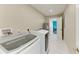 Bright laundry room with modern washer and dryer, white tile flooring, and neutral-colored walls at 3903 Bayside Dr, Bradenton, FL 34210