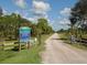Deer Prairie Creek Preserve entrance featuring a sign, fencing, and a gravel path on a sunny day with blue skies at 4153 Fairway Dr, North Port, FL 34287
