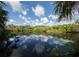 Tranquil lake view with reflections, framed by vibrant greenery and a clear sky at 4153 Fairway Dr, North Port, FL 34287
