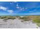 Expansive sandy beach with clear blue skies and scattered clouds, perfect for relaxation and enjoying the coastal scenery at 4508 Mangrove Point Rd, Bradenton, FL 34210