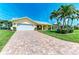 Charming yellow single-story home featuring a brick driveway, attached garage and tropical landscaping at 4508 Mangrove Point Rd, Bradenton, FL 34210